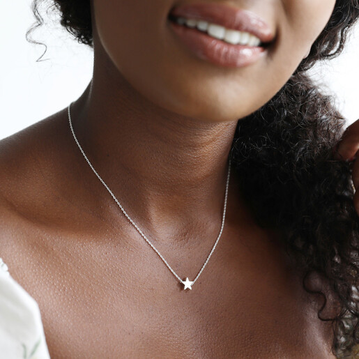 Model wearing silver star bead necklace with initial stamped