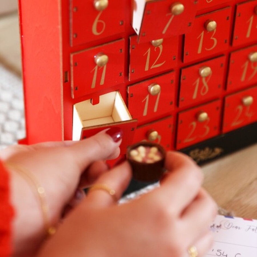 person adding a chocolate to postbox advent calendar drawer