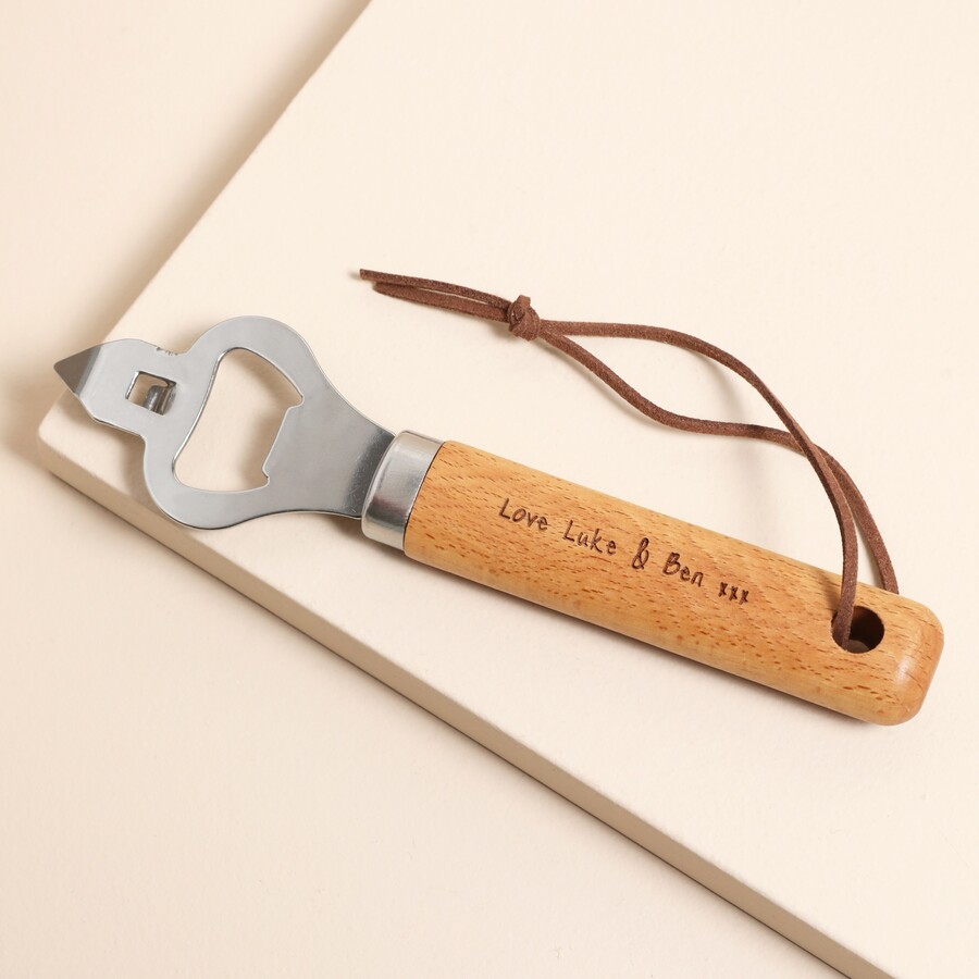 A Wooden Handled Bottle Opener With a Metal End and a Leather Hand Strap Engraved with a Sweet Message on the Handle