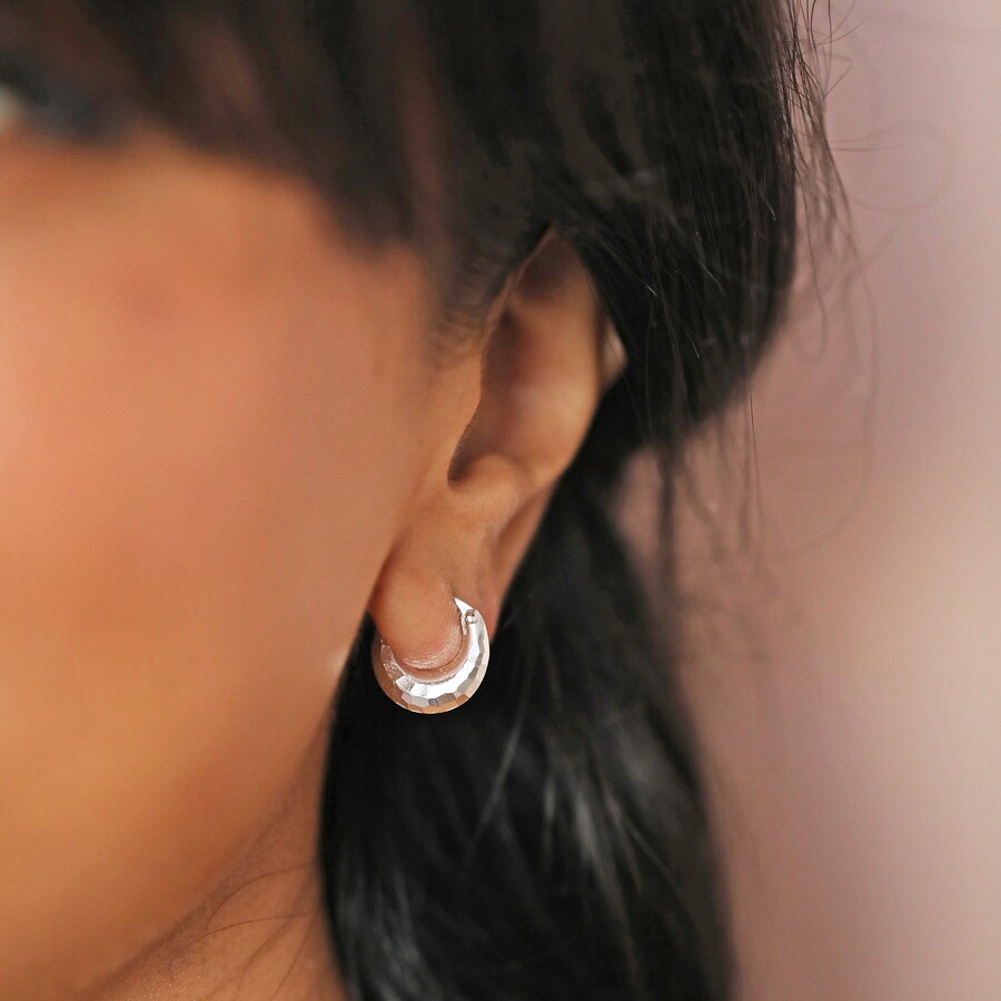 Model wearing curated ear look with Sterling Silver Faceted Dome Huggie Hoop Earrings
