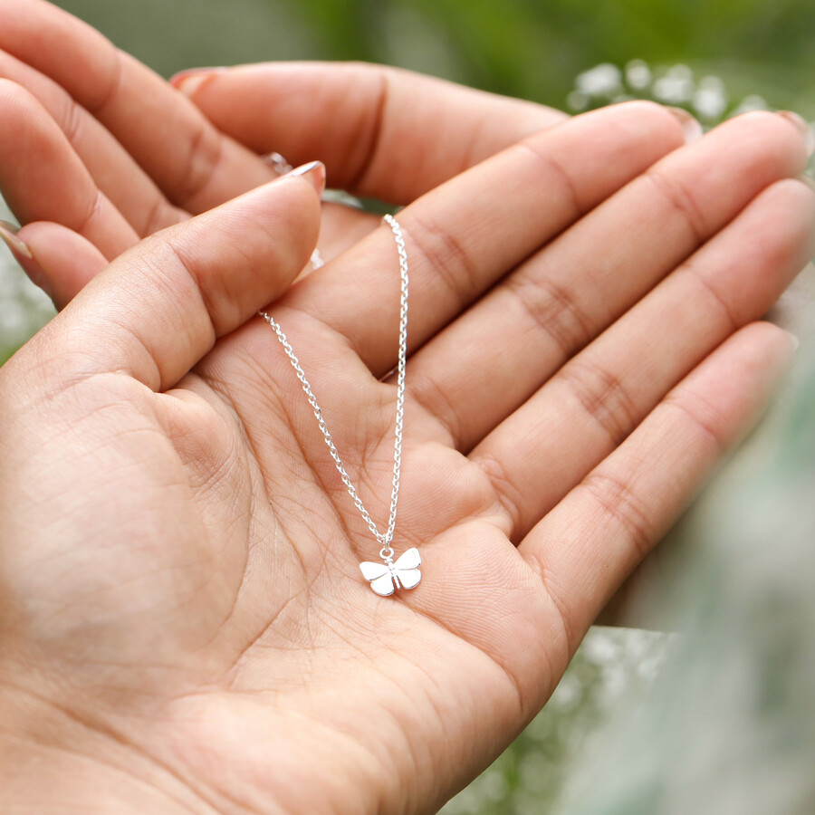 Model holding Tiny Butterfly Pendant Necklace in Silver