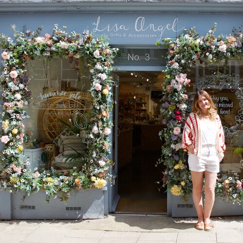 lisa angel standing outside shop with two floral decorated windows
