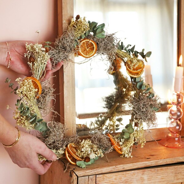 Model placing Gingerbread Christmas Dried Flower Wreath Making Kit on top of wooden counter