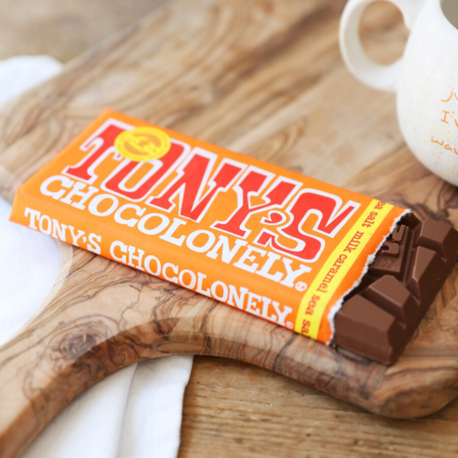 Orange Tony's Chocolonely bar in paper wrapping on a textured table