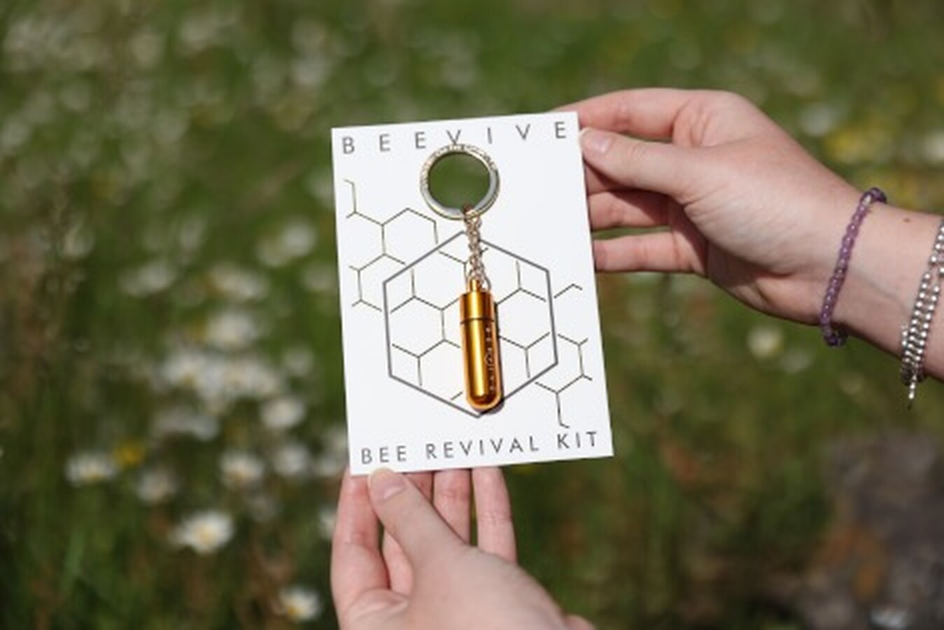 a small, smooth gold beevive keyring with syrup inside