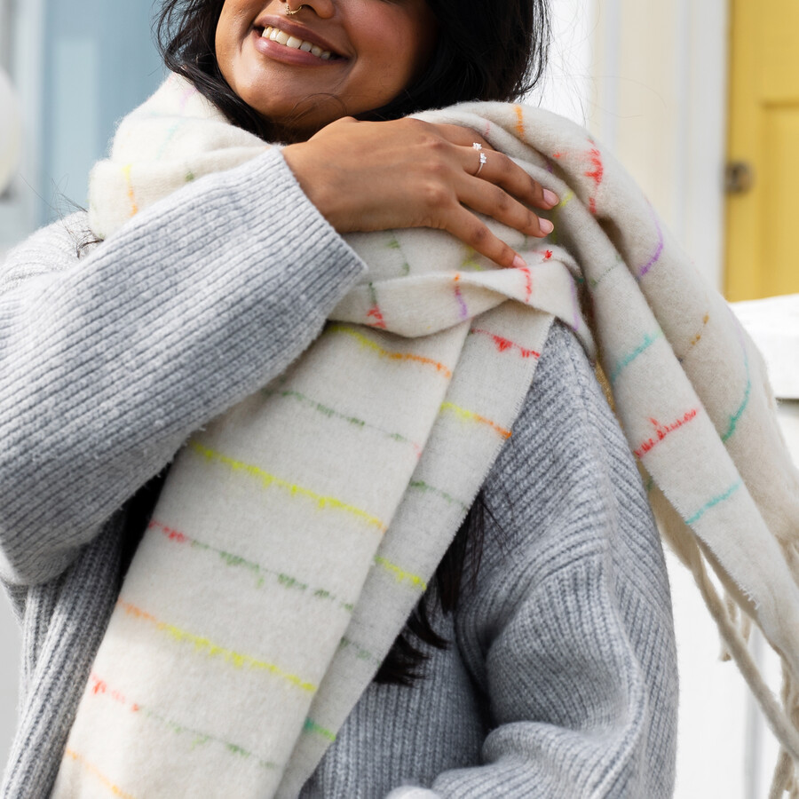 Model Wearing a Cream Knit Winter Scarf with a Subtle Colourful Fleck Through the Knit in Pretty Pinks and Purples