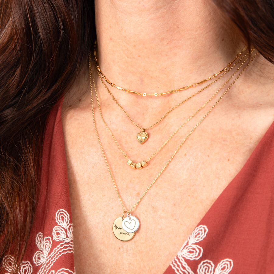 Gold and Silver Pendants With Hand Drawn Messages Hanging From a Gold Chain