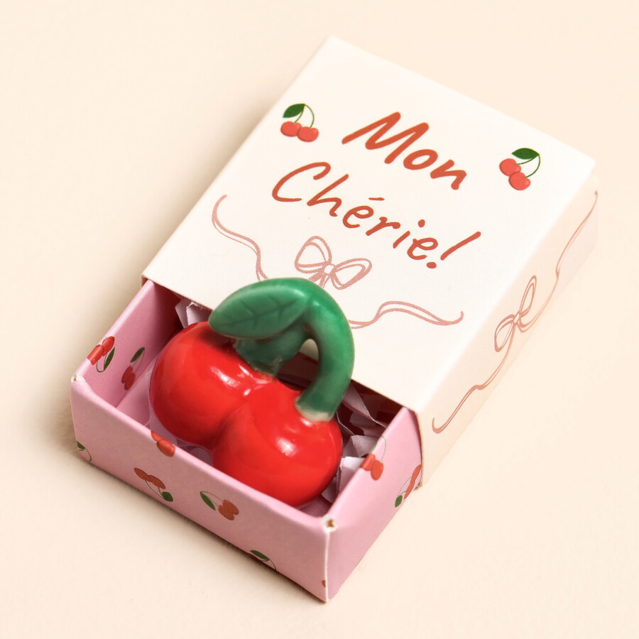 A Tiny Ceramic Cherry Figurine in Red Inside a Mon Cherie Themed Gift Box