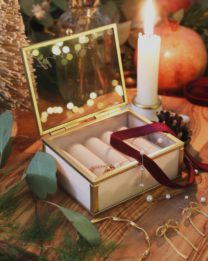 1Mini Glass Jewellery Box in Gold with jewellery and ribbon with a candle on a table 