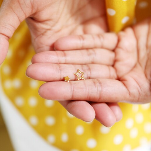 Model Holding Mismatched Star Stud Earrings in Gold