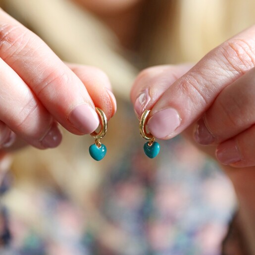 Model Holding Teal Enamel Heart Charm Huggie Hoop Earrings