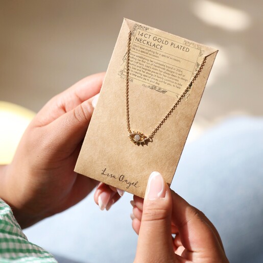 Model Holding Clear Crystal Eye Charm Necklace in Gold in Packaging