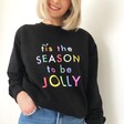 Model Wearing Tis The Season to be Jolly Sweatshirt in Black leant against a wall