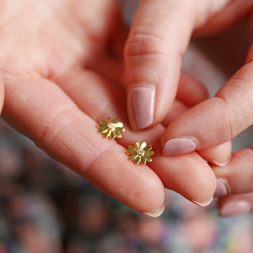 Model Holding Daisy Stud Earrings in Gold 