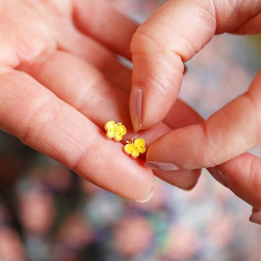 Model Holding Enamel Butterfly Stud Earrings in Gold