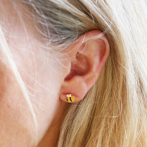 Model Wearing Mismatched Enamel Bee and Sunflower Stud Earrings in Gold