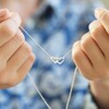 Model Holding Delicate Tiny Interlocking Hearts Necklace in Silver