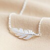 Silver Feather Necklace on Beige Fabric