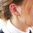 Wearing Wide Gold Stainless Steel Huggie Hoop Earrings as part of a Curated Ear