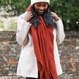Model wearing terracotta Personalised Embroidered Lambswool Scarf with white coat