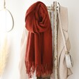 Terracotta Personalised Embroidered Lambswool Scarf hanging on coat rack