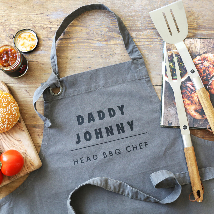 Personalised 'Head BBQ Chef' Grey Apron on top of wooden counter with utensils around