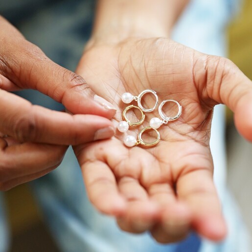 Model Holding Ladies' Sterling Silver Pearl Huggie Hoops