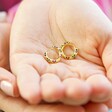 Hands Holding Small Thick Rainbow Crystal Huggie Hoop Earrings in Gold