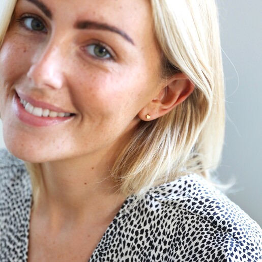 Model Wears Tiny Stainless Steel Heart Stud Earrings in Gold