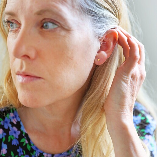 Female Model Wearing Tiny Stainless Steel Star Stud Earrings in Gold