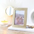 gold hammered photo frame on dark wood table with mirror in background on white wall