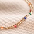 Close Up of Rainbow Enamel Ball Chain Layered Anklet in Gold on Beige Coloured Fabric