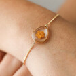 Close Up of Model Wearing October Pressed Birth Flower Charm Bracelet in Gold