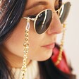Model Wearing Chunky Loop Glasses Chain in Gold with Beige Background