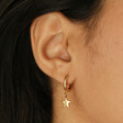 Model Wearing Antiqued Effect Star Charm Huggie Hoop Earrings in Gold