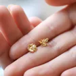 Mismatched Daisy and Bee Stud Earrings in Gold in Between Model's Fingers