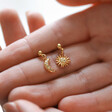 Model Holding Mismatched Moon and Sun Drop Earrings in Gold in Between Fingers