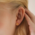 Close Up of Model Wearing Small Flower and Pearl Stud Earrings in Gold