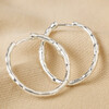 Textured Hoop Earrings in Silver Laid on Beige Coloured Fabric