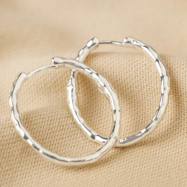Textured Hoop Earrings in Silver Textured Hoop Earrings in Silver Laid on Beige Coloured Fabric