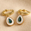 White and Green Enamel Teardrop Huggie Hoop Earrings in Gold on Beige Fabric