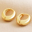 Wide Domed Huggie Hoop Earrings in Gold on Natural Coloured Fabric