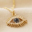 Blue Crystal Eye Pendant Necklace in Gold on Beige Fabric