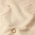 Floral Halo Pendant Necklace in Gold Full Length on Beige Fabric