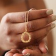 Model Holding Floral Halo Pendant Necklace in Gold