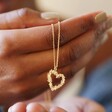 Model Holding Floral Heart Pendant Necklace in Gold
