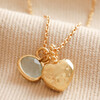 Close Up of Pendants on Heart and Moonstone Pendant Necklace in Gold with Beige Fabric in Background