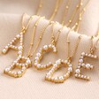 A, B, C, D, and E Irregular Pearl Initial Necklace in Gold on Beige Fabric