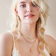 Model Wearing E Irregular Pearl Initial Necklace in Gold Layered With Other Necklaces