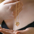 Model Holding Up Large 3D Molten Heart Pendant Necklace in Gold